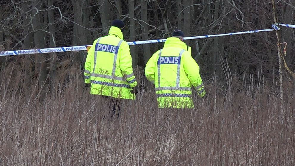 Poliser vid avspärrning i skog.