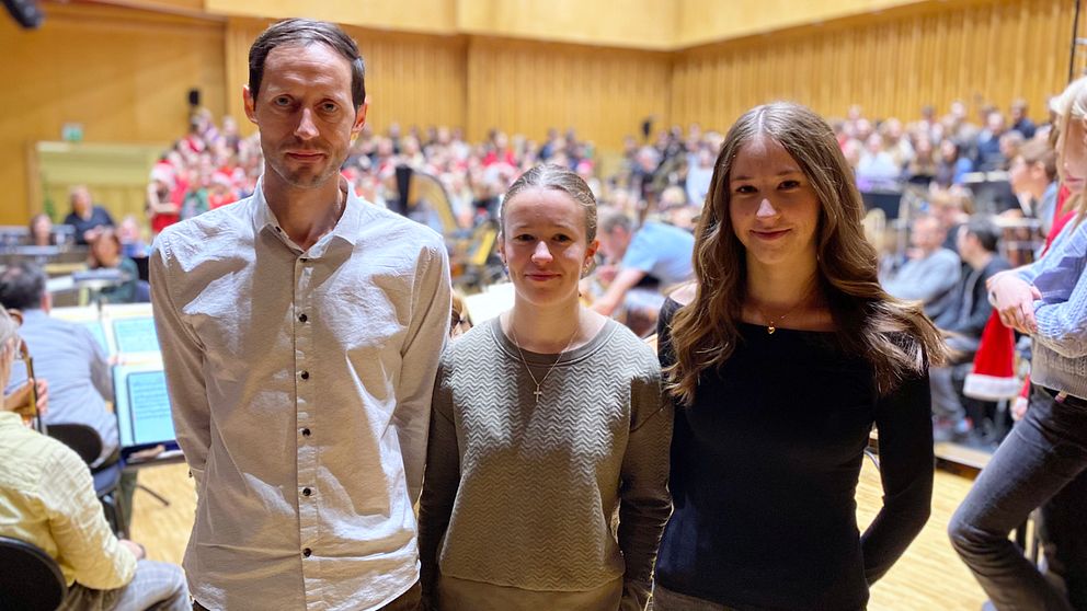 en man och två tjejer står framför en kör