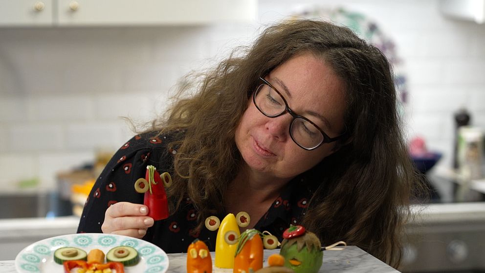 Kvinna tittar på figurer gjorda av grönsaker