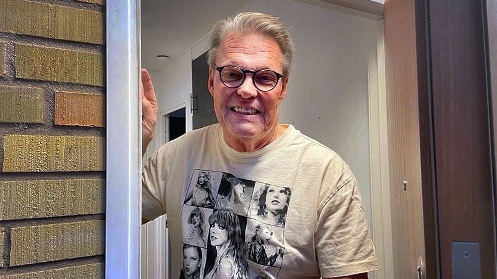 Anders Eggegård står i en dörröppning och håller i dörrkarmen. Han bär en t-shirt med svartvitt tryck av olika bilder på Taylor Swift. Bakgrunden visar en del av en trappa och en vägg i en interiör.