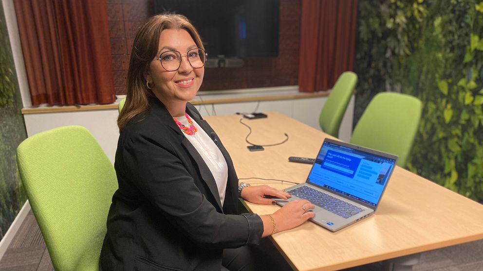 Rektorn på vuxenutbildningen i Sundsvall Jennie Sjögren sitter vid ett bord med en laptop framför sig och vuxenskolans hemsida där en egenutvecklad AI-assistent finns som kan svara på frågor.