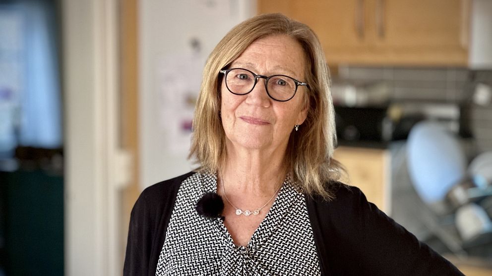 En nöjd Birgitta Sjölin hemma vid sitt kök blickar in i kameran.