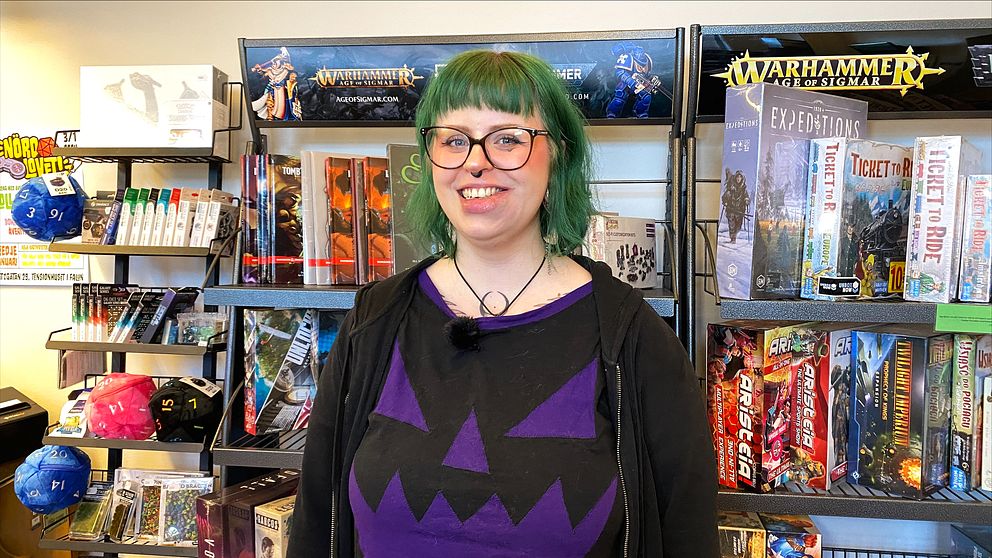 en kvinna framför en vägg med brädspel i en spelbutik
