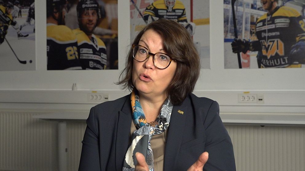 Person i kostym framför hockeybilder på väggen.