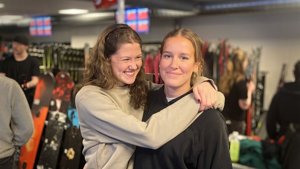 Hilda Wadsborn Taube och Vilma Holmqvist står och håller om varandra inne en skiduthyrning i Åre.