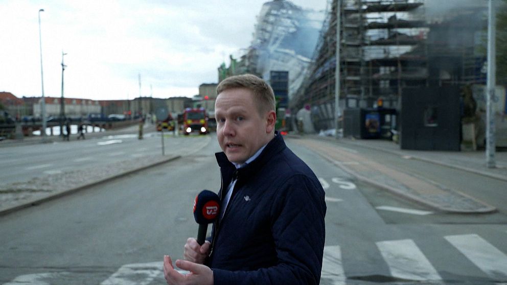 En man står framför den raserade Börsen i Köpenhamn.