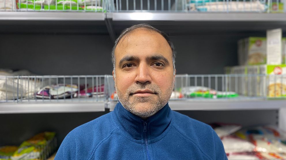 Chetan Sharma i sin indiska matbutik i Skellefteå. Han bär en blå fleecetröja och i bakgrunden syns butikshyllor med mat.