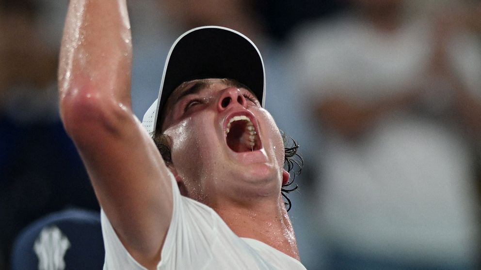En tennisspelare firar triumferande med uppsträckt arm efter en viktig poäng under en match. Bakgrunden visar en entusiastisk publik som hejar.