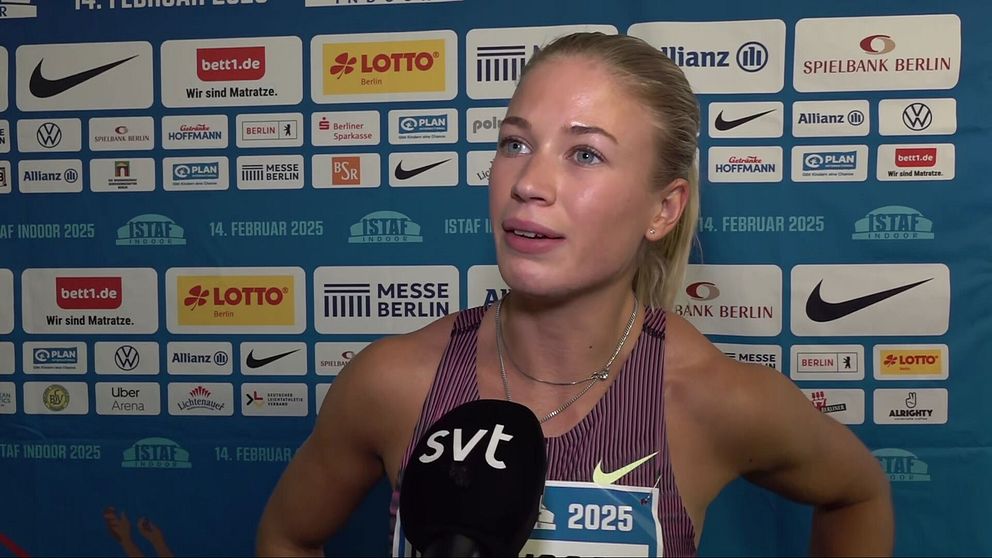 En idrottare, iklädd sportkläder med nummerlapp ”2025”, intervjuas av SVT. I bakgrunden syns en sponsorvägg fylld med logotyper från olika företag såsom Lotto, Nike, och Allianz.