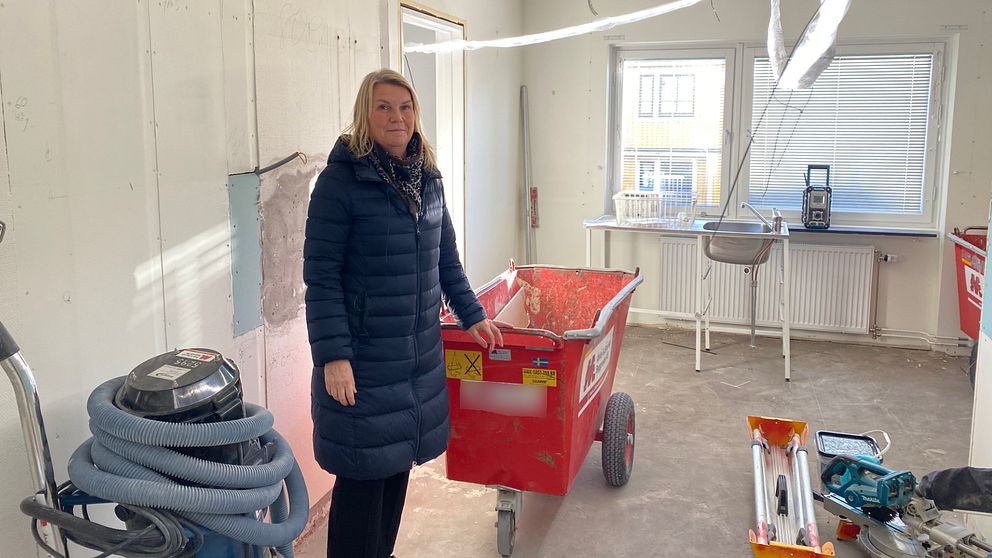 Bild på kvinna i blå jacka inne i en lägenhet som renovera i Motala.