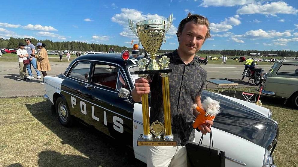 Arvid Jonsson, med en pokal framför sin polisbil.