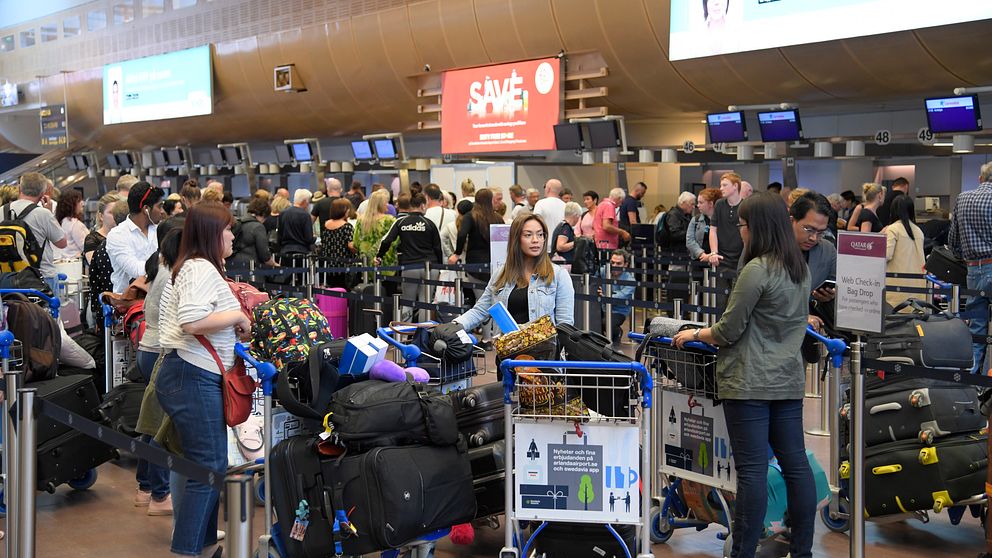 Personer som står och väntar på att checka in bagage på en flygplats.