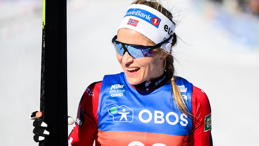 Skidåkare i tävlingsdräkt håller en skida; nummerlapp 32.