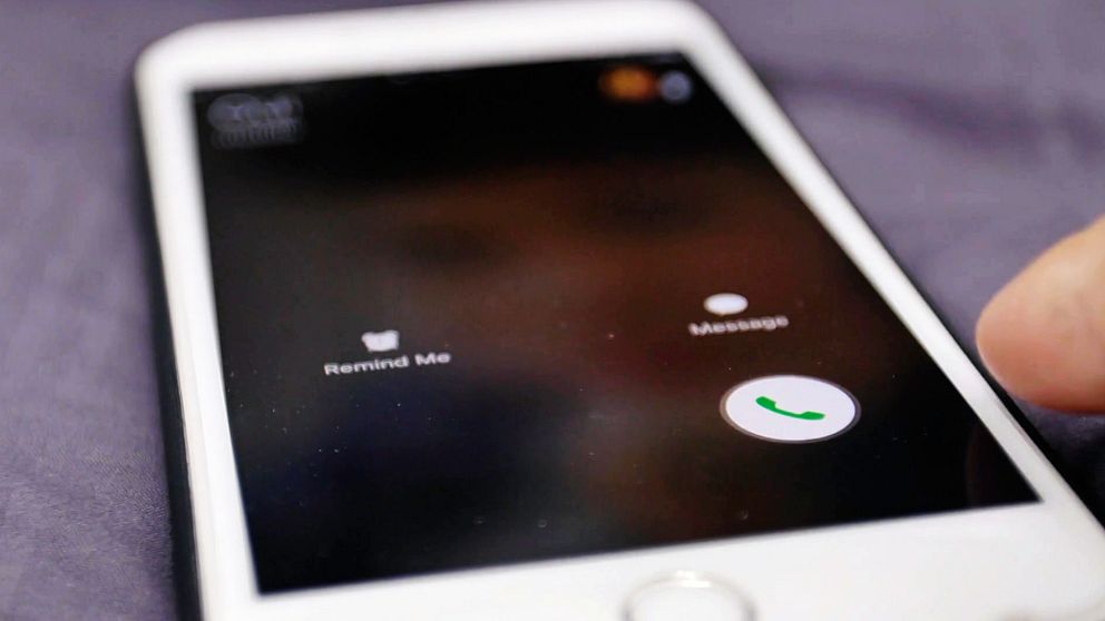Skärmen på en smartphone som visar en inkommande samtalsmeny med alternativet ”Remind Me”, ”Message” och en grön telefonikon för att svara på samtalet. En hand är i färd med att trycka på telefonikonen.