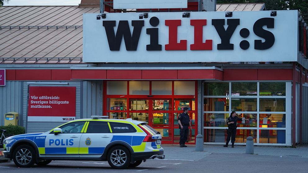 Två poliser står utanför Willys i Nybro bredvid en polisbil