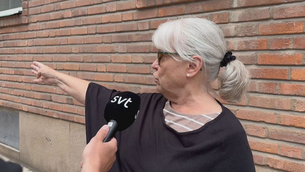 äldre kvinna som blir intervjuad pekar med högerarmen
