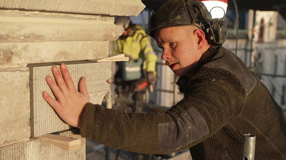 Stenhuggaren Philip Gullberg justerar stenblock vid byggarbetsplats.