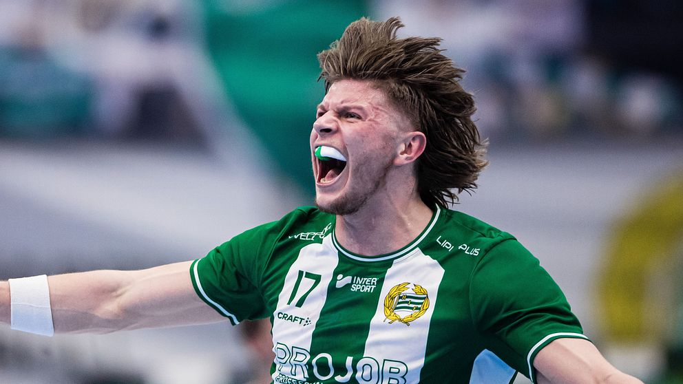 Fotbollsspelare i grönvitrandig tröja firar med utsträckta armar på planen.