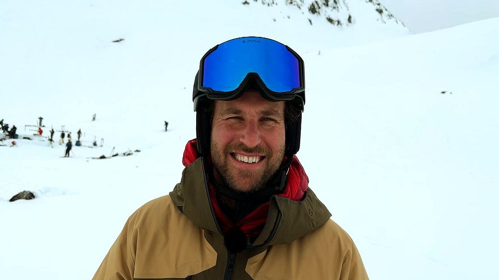 Person med skidkläder och hjälm på snötäckt fjäll.