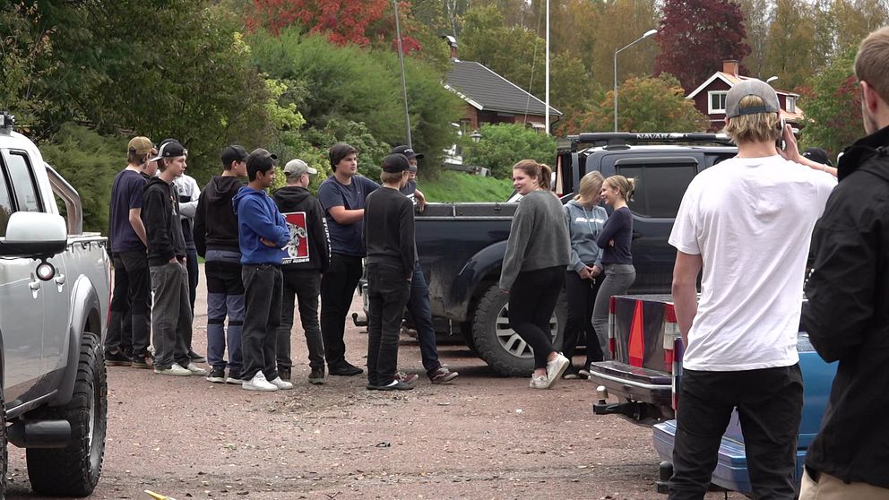 Ett gäng ungdomar står vid en parkering med A-traktorer