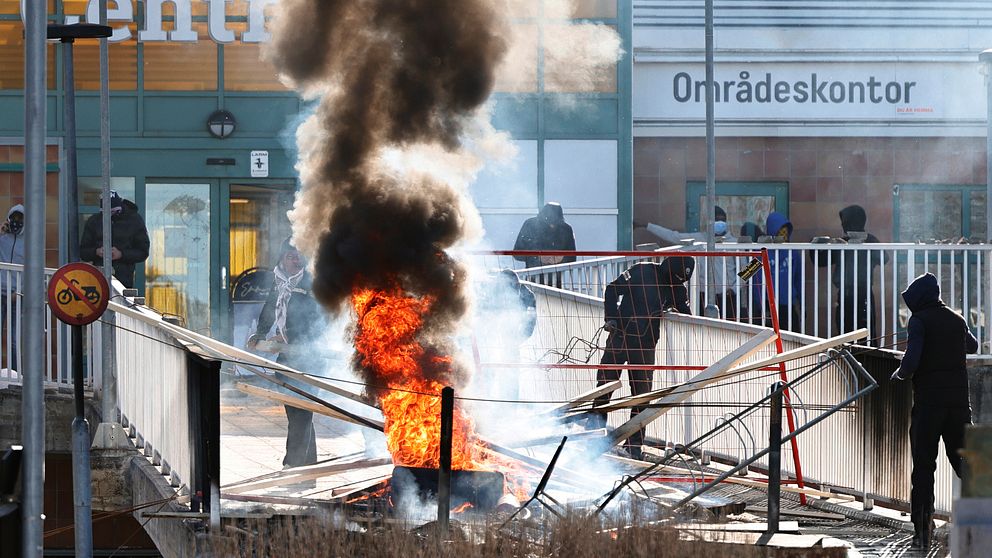Personer gör en barikad med brinnnade bildäck och andra föremål vid Ringdansen centrum, i samband med upplopp i Navestad i Norrköping på påskdagen