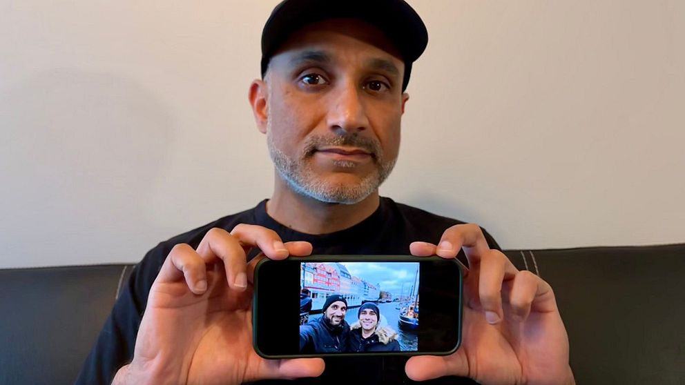 Qasim håller upp en mobil med en bild på hans bror som dog