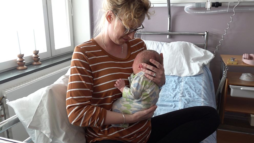 Person i randig tröja håller en baby på ett sjukhusrum på Lycksele BB.
