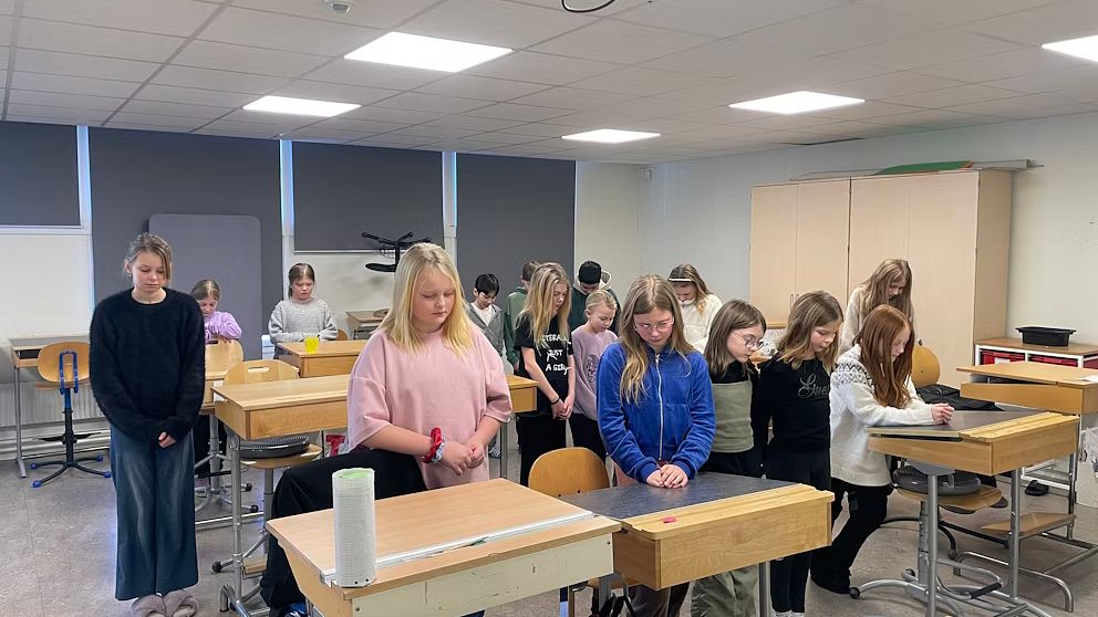 Skolbarn i ett klassrum med bänkar.