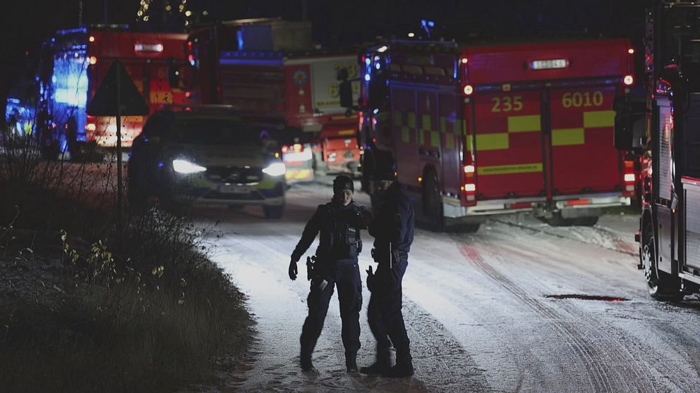 Två poliser står framför polisbilar och brandbilar i Kungsängen.