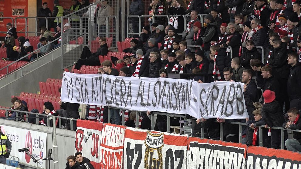 En stor grupp supportrar på läktaren håller upp en banner med texten ”Vi ska inte ge er all svenskan” följt av ”GFA 188”. Många av dem bär lagets färger och sjunger, vilket skapar en intensiv stämning under matchen. Bannerna i bakgrunden förstärker känslan av klubbsupport.