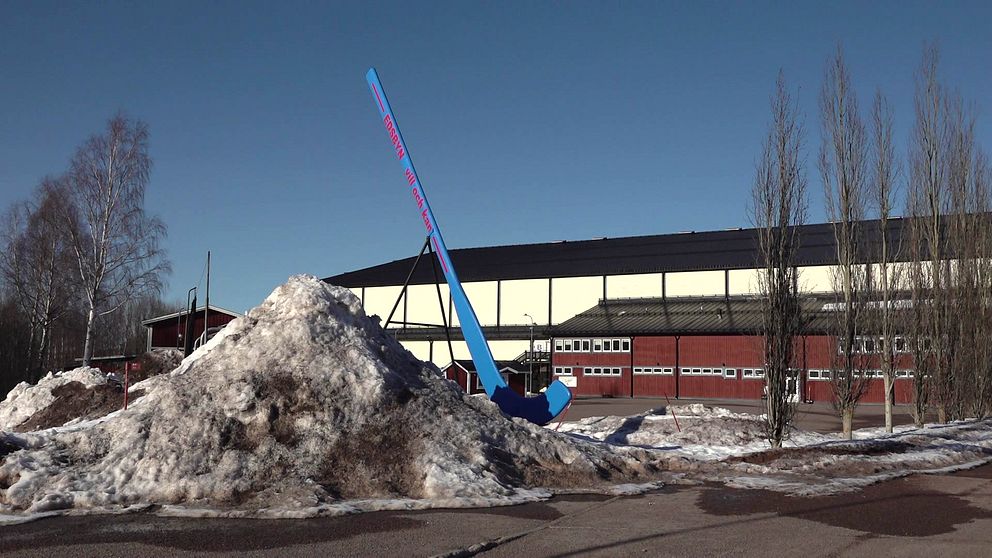 Bandyklubba i storformat framför bandyhall