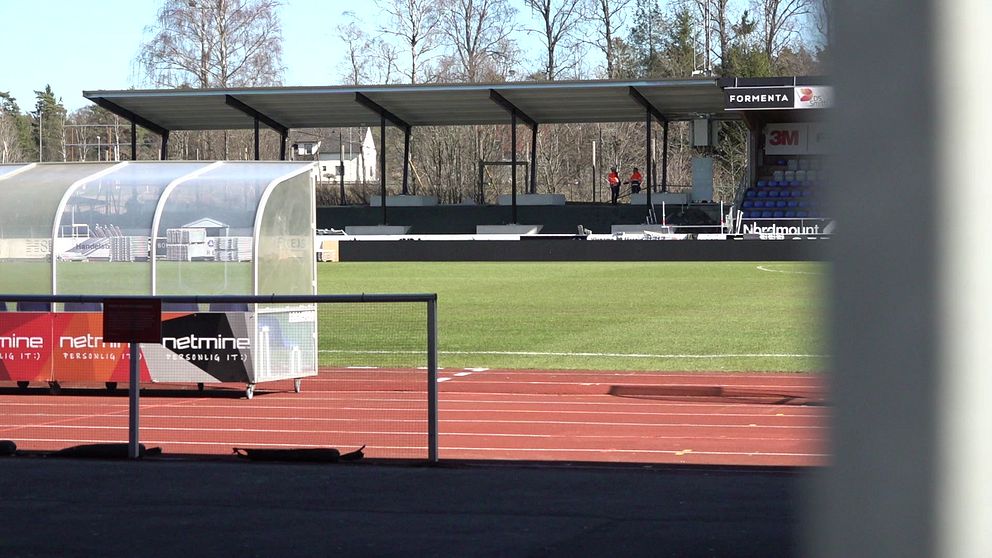 Tom fotbollsstadion med avbytarbänk och tomma läktare.