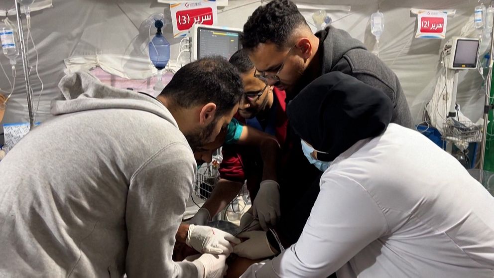 Flera personer hjälps åt att behandla patient på sjukhus i Gaza