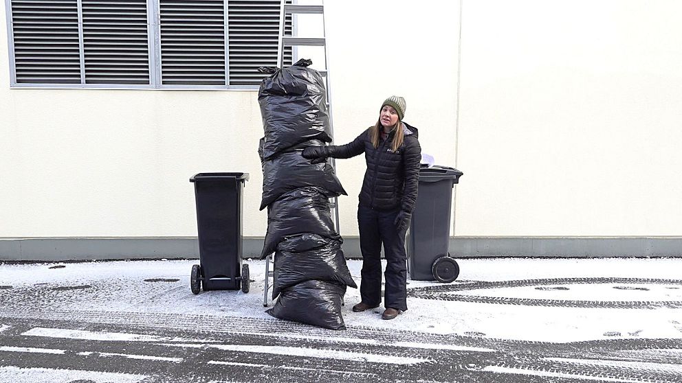 reporter står brevid hög med sopsäckar