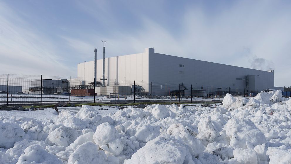 Stor fabrik i vinterlandskap med snö framför byggnaden.