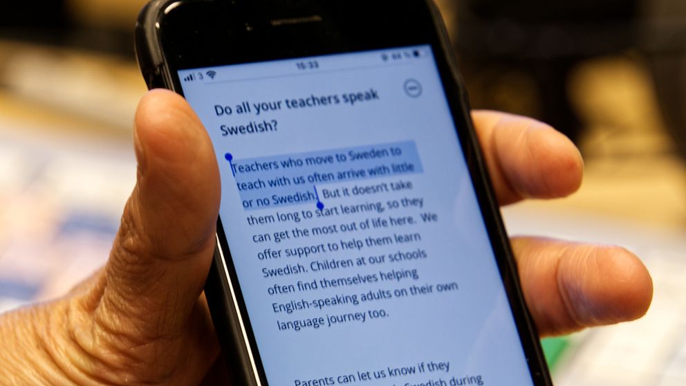 En hand som håller en mobiltelefon, som visar IES hemsida.