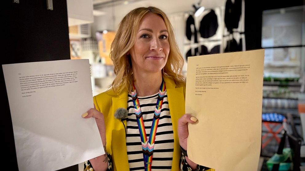Person i gul kavaj håller upp två papper inne i en möbelaffär.