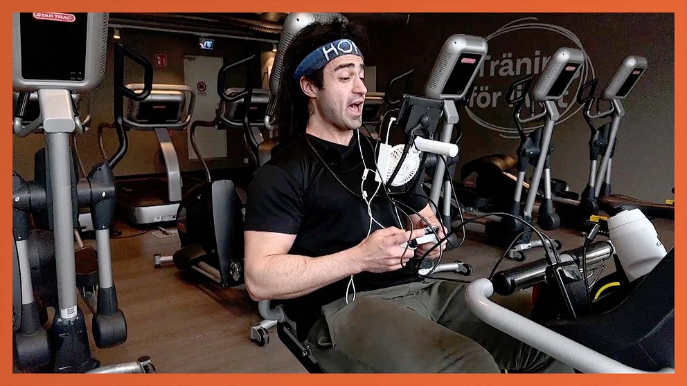 Person tränar på motionscykel på gym, omgiven av träningsmaskiner.