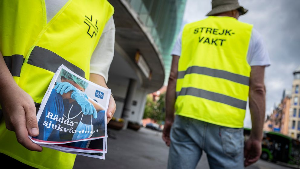 En strejkande vårdarbetare håller i en pamflett.