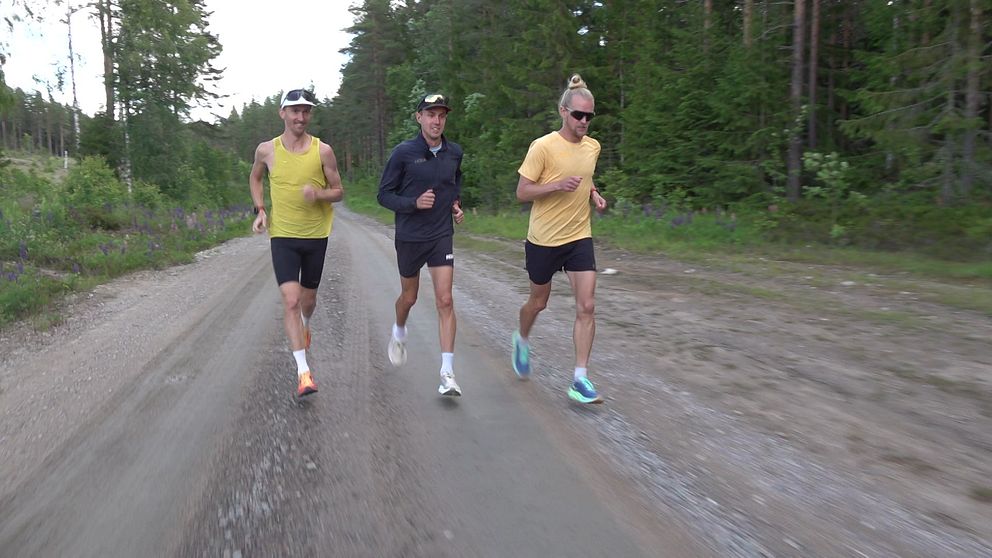 Tre män som springer på en skogsväg
