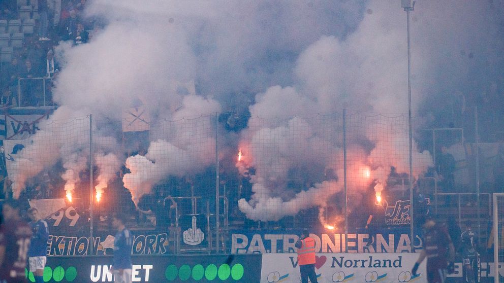 Fotbollsfans bränner pyroteknik och skapar tätt rökmoln i publikhavet.