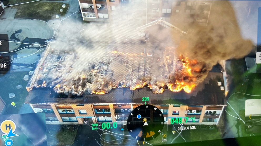 En bild från räddningstjänsten drönare som visar ett lägenhetshus på körfältet som brinner.