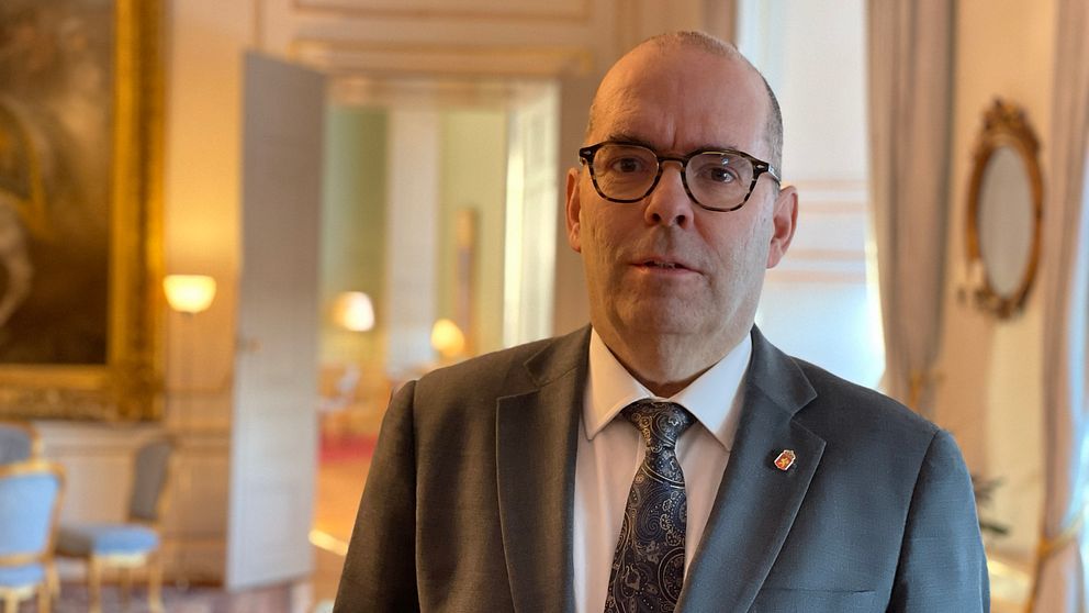 Bild på Carl Fredrik Graf inne på slottet i Linköping. Han är klädd i grå kavaj och bär slips och svarta glasögon.