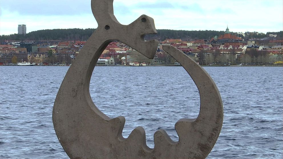 Skulptur vid Vättern med Huskvarna stadssiluett i bakgrunden.