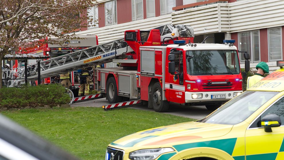 Brandbil och ambulans står utanför ett lägenhetshus där det har brunnit.