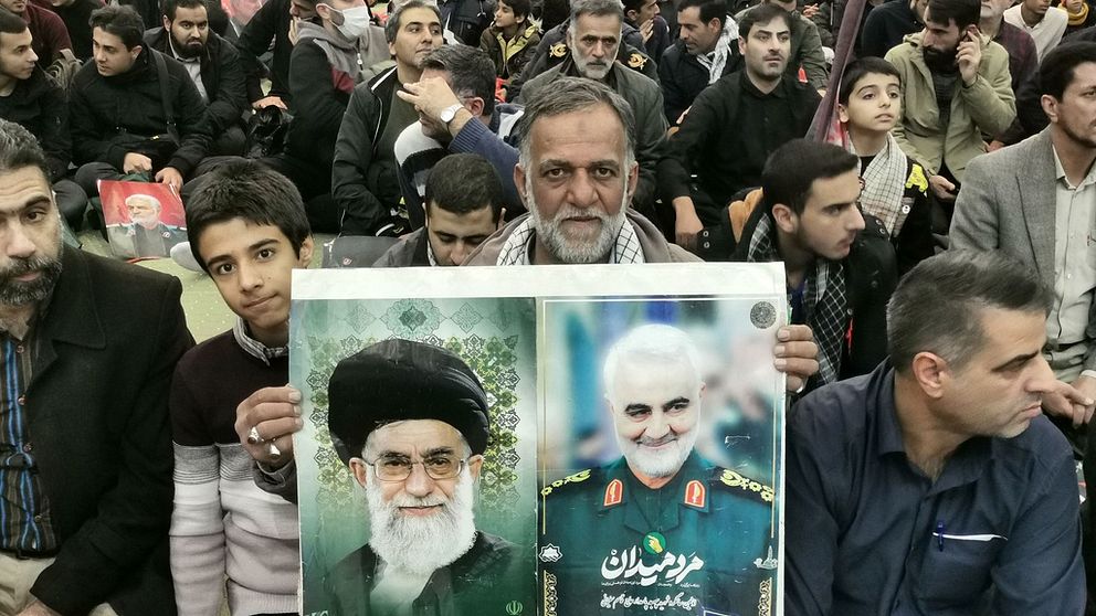 En man håller porträtt av den högsta ledaren Ayatollah Ali Khamenei och den dödade iranske befälhavaren Qasem Soleimani