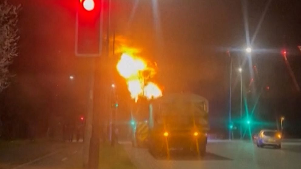 Brand bakom lastbil vid ett trafikljus. Röd ljussignal lyser, andra fordon passerar.