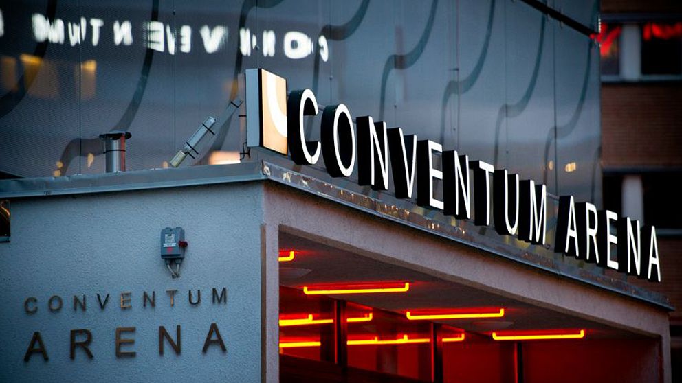 Ingången till Conventum Arena med upplyst skyltskrift och röda lampor under taket.