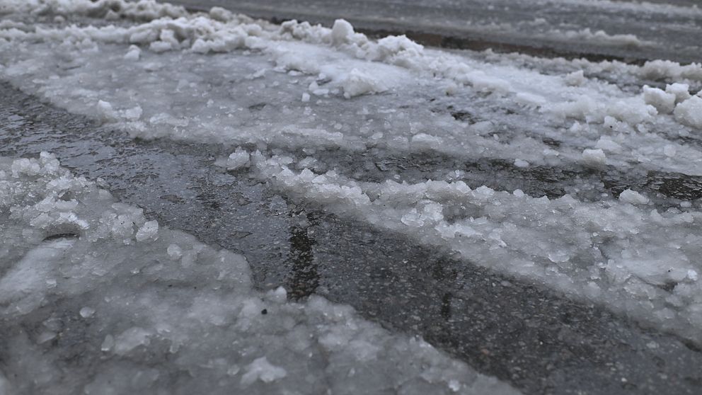 Snö och is täcker en asfalterad väg.