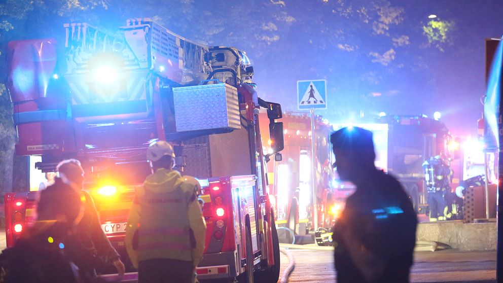 Flera brandbilar med blåljus på en gata, nattetid